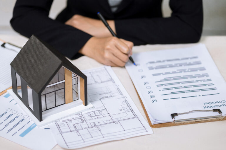 Businesswoman checking document checklist on clipboard near home model and floor plan. Concept of house buying process, mortgage agreement, renovation and construction plan.